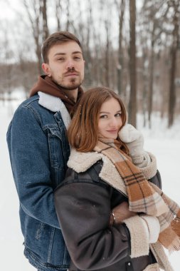 Karla kaplı bir ormanda rahat bir anın tadını çıkaran bir çift. Sıcak kıyafetleri kış manzarasıyla çelişiyor. Romantik ve iç açıcı bir atmosfer yaratıyorlar..
