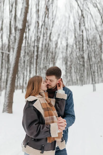 Romantik bir çift, karlı bir ormanda, sevgi ve sıcaklıkla sarmalanmış bir şekilde, baş döndürücü kış manzarasının ortasında, aşklarını güzel bir şekilde sergiliyorlar.