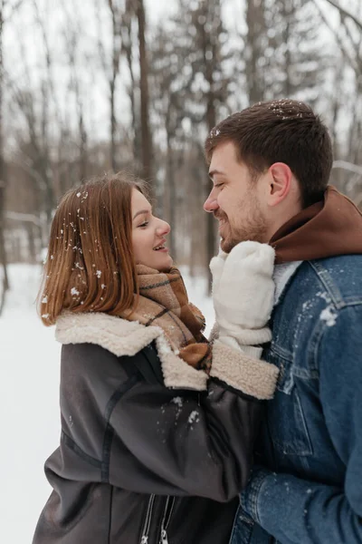 Neşeli bir çift, zarif kar taneleriyle çevrili sakin bir karlı ormanda derin duygularla dolu romantik bir kış ortamı yaratarak sevgi dolu bir anı paylaşıyor.