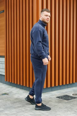 Bir erkek model zarif bir şekilde modern desenli bir duvar zeminine karşı şık bir donanma spor giysisi sergiliyor. Atletik moda kavramları ve stilleri için mükemmel.