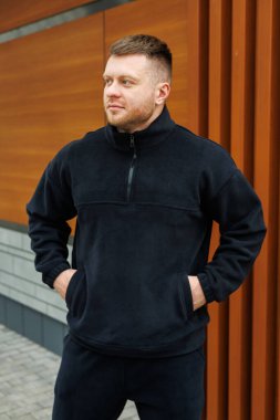 Moda bir genç adam kentin hareketli bir bölgesinde, modern şehir tarzıyla mükemmel bir şekilde harmanlanmış, modaya uygun, siyah yün bir ceket giyerek özgüvenle duruyor.