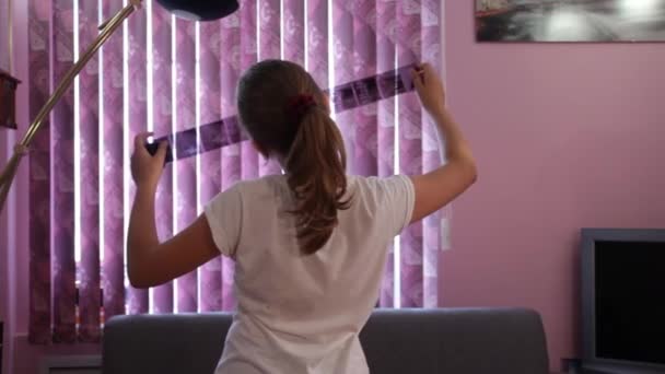 Tini lány gazdaság film negatív a kezében, és keres fényképészeti film. — Stock videók