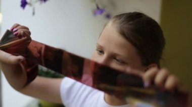 Genç kız elinde film negatif tutarak ve ilgi ile fotoğraf filmi görünümlü.