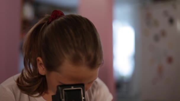 Adolescent fille regarde dans la mine d'un appareil photo de format moyen visant à nous, prendre des photos de vous . — Video