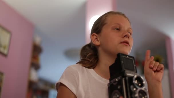 Teen girl looks into the mine of a medium format camera aimed at us, taking picture of you. — Stock Video