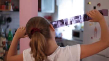 Genç kız elinde film negatif tutarak ve ilgi ve gülümseme ile fotoğraf filmi görünümlü.