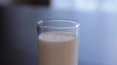 Bir bardak süt. kamera süt ile cam etrafında hareket eder. Close. kamera sola hareket eder. bulanık arka plan.