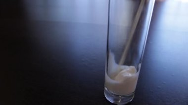 bir bardak süt. Süt ahşap bir masa üzerinde uzun bir bardağa dökülür. Dökme işlemi.