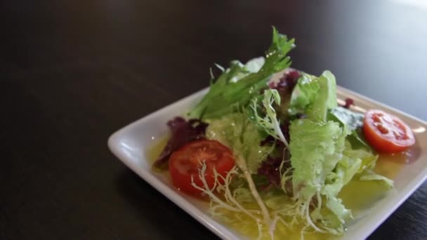 绿色生菜 西红柿和橄榄油在方形白盘 摄像机在它周围向左移动 — 图库视频影像