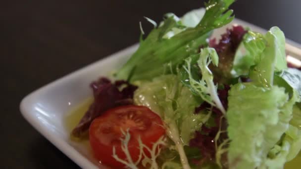 绿色生菜 西红柿和橄榄油在方形白盘 摄像机在它周围向左移动 — 图库视频影像