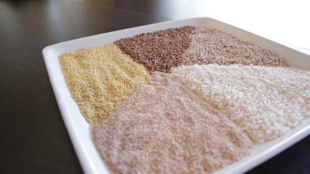 Diversi tipi di cereali su un unico piatto. grano saraceno, riso, miglio, orzo, quinoa. la fotocamera si muove intorno a questo a sinistra — Video Stock