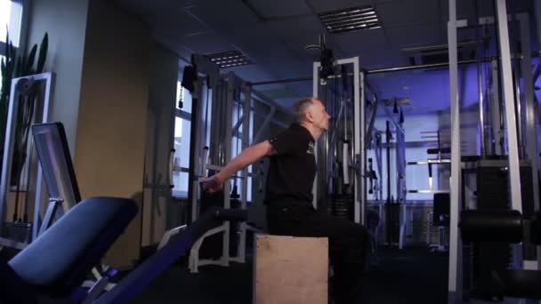 En man av åldern utför gemensam gymnastik för ryggen i gymmet. Uträtning av armarna bakom ryggen. Kopiera utrymme. — Stockvideo
