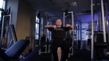 Çağın bir adam spor salonunda kollar için ortak jimnastik yapar. Ön kol dönüşü. Kopyalama alanı.