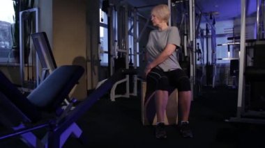 Yaşlı bir kadın, vücudun ait yerlerini oturmuş bir pozisyonda yapar. Space.front view.glide cam görüntüleri kopyalayın