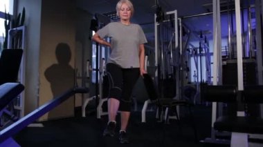 Yaşlı bir kadın ayakta ayakta döner.ortak jimnastik uygular. Space.front view.glide cam görüntüleri kopyalayın