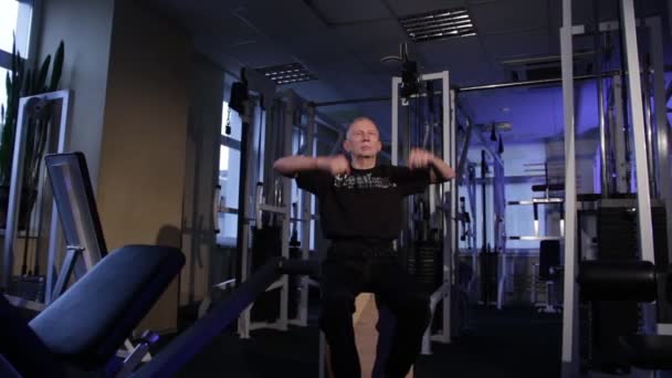 Een man van de leeftijd voert gezamenlijke gymnastiek voor de armen in de sportschool. Onderarm rotatie. Ruimte kopiëren. — Stockvideo