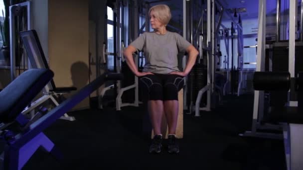 将膝盖上的腿伸长到坐姿。一位练习联合体操的老年妇女。复制空间 — 图库视频影像