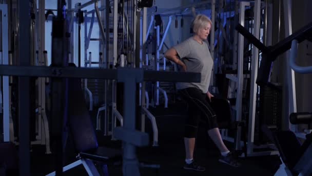 Een vrouw van leeftijd draait in haar voet staande. het beoefenen van gezamenlijke gymnastiek. Kopieer ruimte. zijaanzicht — Stockvideo