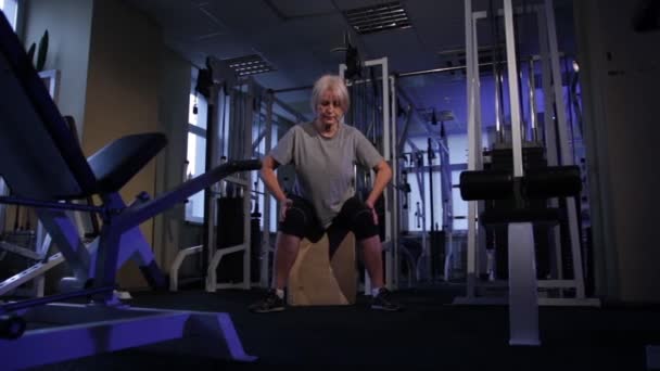 Mujer anciana realiza ejercicio isométrico, arrodillándose a los lados y la vista retro.front. — Vídeos de Stock