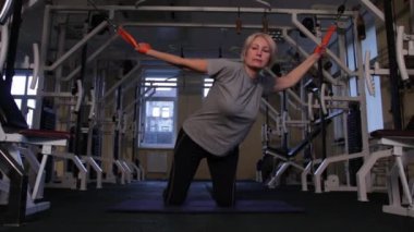 Yaşlı kadın kinesiyolojik egzersiz yapar, yanlara ve arkaya diz çöküp.ön görünümde. Kopyalama alanı