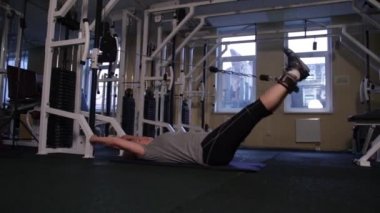 Yaşlı kadın bir crossover simülatörü üzerinde lomber bölge için kinesiyolojik egzersiz yapar. Kopyalama alanı.