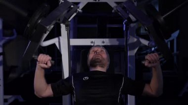 Genç bir adam simülatöre bench presi yapar.düşük anahtar çerçevesi