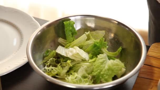 El chef pone hojas de ensalada, rodajas de naranja, mango, aguacate en un bol y las mezcla con aceite de oliva — Vídeos de Stock