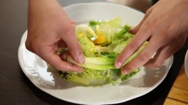 Şef salata yaprakları, portakal dilimleri, mango, bir tabakta zeytinyağı ile karışık avokado koyar