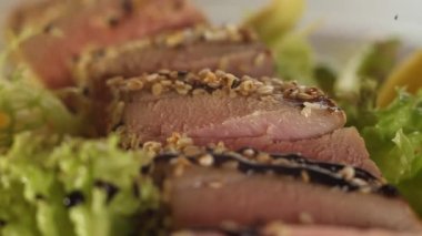 Balsamik sos damlacıkları ton balığı parçaları ve yeşil salata yaprakları bir tabak üzerine düşmek. Makro.yakın çekim