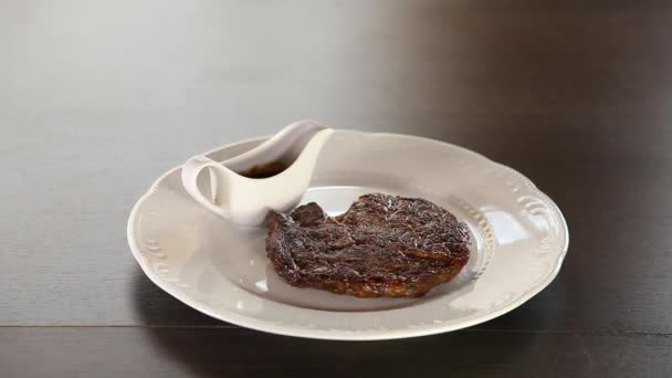 Kuchař položí hovězí steak na talíř, ozdobí jej bylinkami, rozstříkne se olivovým olejem a posychne solí a pepřem — Stock video