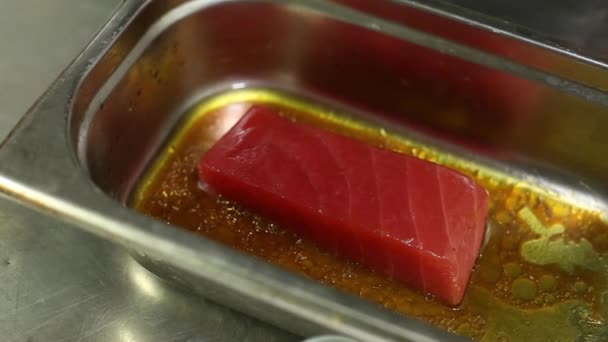 Der Koch wendet ein Stück rohen Thunfisch in einer Schüssel mit Marinade. Großaufnahme — Stockvideo