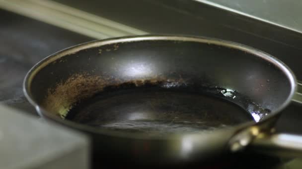 Шеф-повар кладет кусок филе тунца, завернутый в кунжут, на горячую сковородку — стоковое видео