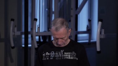 Yaş bir adam spor salonunda boyun için ortak jimnastik yapar. Eğilir baş öne. Close