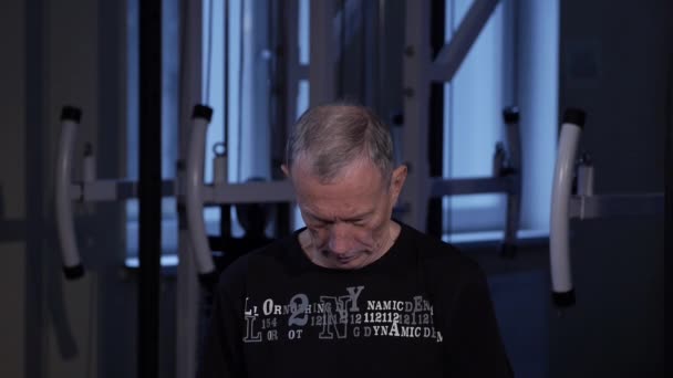 Een man van de leeftijd voert gezamenlijke gymnastiek voor de nek in de sportschool. Kanten gaan naar voren. Close-up — Stockvideo