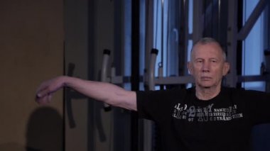 Bu yaştaki bir adam spor salonunda bilek için ortak jimnastik yapar. Kopyalama alanı