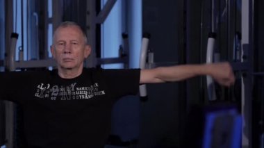 Çağın bir adam spor salonunda kollar için ortak jimnastik yapar. Ön kol dönüşü. Kopyalama alanı