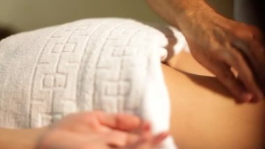 Erkek masör masaj bir spa salonunda sıcak taşlar kullanarak bir kadın arka kalça. Close
