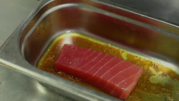 Кухарі рук перевертають шматок сирого тунця в мисці маринаду. крупним планом — стокове відео