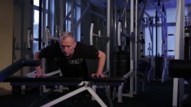 yaşlı bir adam spor salonunda banktan kendini iter. Kopyalama alanı.