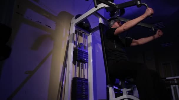 Een jonge man doet een oefening op de borstspieren op de Simulator. ruimte kopiëren — Stockvideo