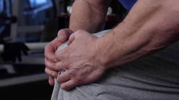 Мощный спортсмен делает изометрические упражнения, сопротивляясь колени с его hands.side view.close-up — стоковое видео