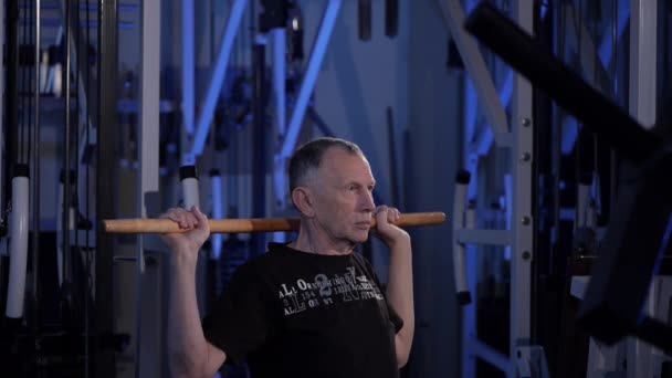 Homme âgé fait un exercice isométrique avec un bâton, le tenant derrière l'arrière de sa vue de la tête.côté. — Video