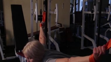 Yaşlı kadın kinesiyolojik egzersiz yapar.crossover simülatöründe büküm.close-up.side view