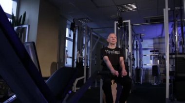 Yaş bir adam spor salonunda parmaklar için ortak jimnastik yapar. Yumruğunu sıkıyor ve amcana vuruyor, kollarını önünde alt katta niçin çıkarıyorsun. Kopyalama alanı.