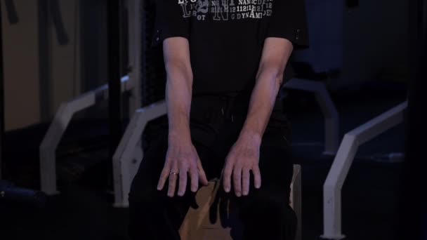 Un hombre de la edad realiza gimnasia articular para los dedos en el gimnasio.Apretando y desabrochando el puño, los brazos hacia fuera delante de usted bajando.Espacio de copia — Vídeos de Stock