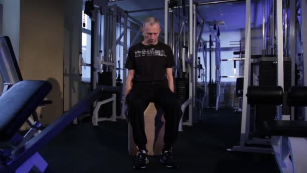 Человек в возрасте выполняет совместную гимнастику для шеи в gym.Tilts голову forward.Copy space.Wide угол выстрела — стоковое видео