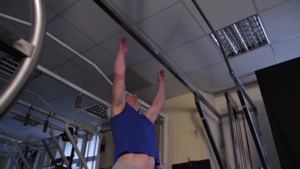 Een machtige atleet van de leeftijd voert een Planche op een bar — Stockvideo