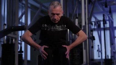 Yaşlı bir adam izometrik egzersiz yapar, yanlara diz çöküp.ön görüşte. Kopyalama alanı