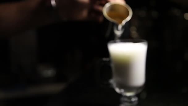 Een barista hand giet koffie in een glas Mochaccino of latte. Onscherpe achtergrond. Ruimte kopiëren — Stockvideo