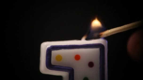 Zblízka se rozsvítí sváteční svíčka ve tvaru čísla jedna, nádherné úvahy kolem ohně. Pak plamen zhasne. Makro — Stock video